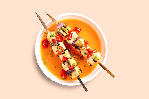 Tofu SkewersA plate of grilled halloumi and vegetable skewers sits atop a pool of bright orange carrot soup.