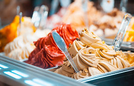 An assortment of colorful Italian ice is shown in a close-up view. The flavors from the left are: orange, strawberry, pistachio, and hazelnut.