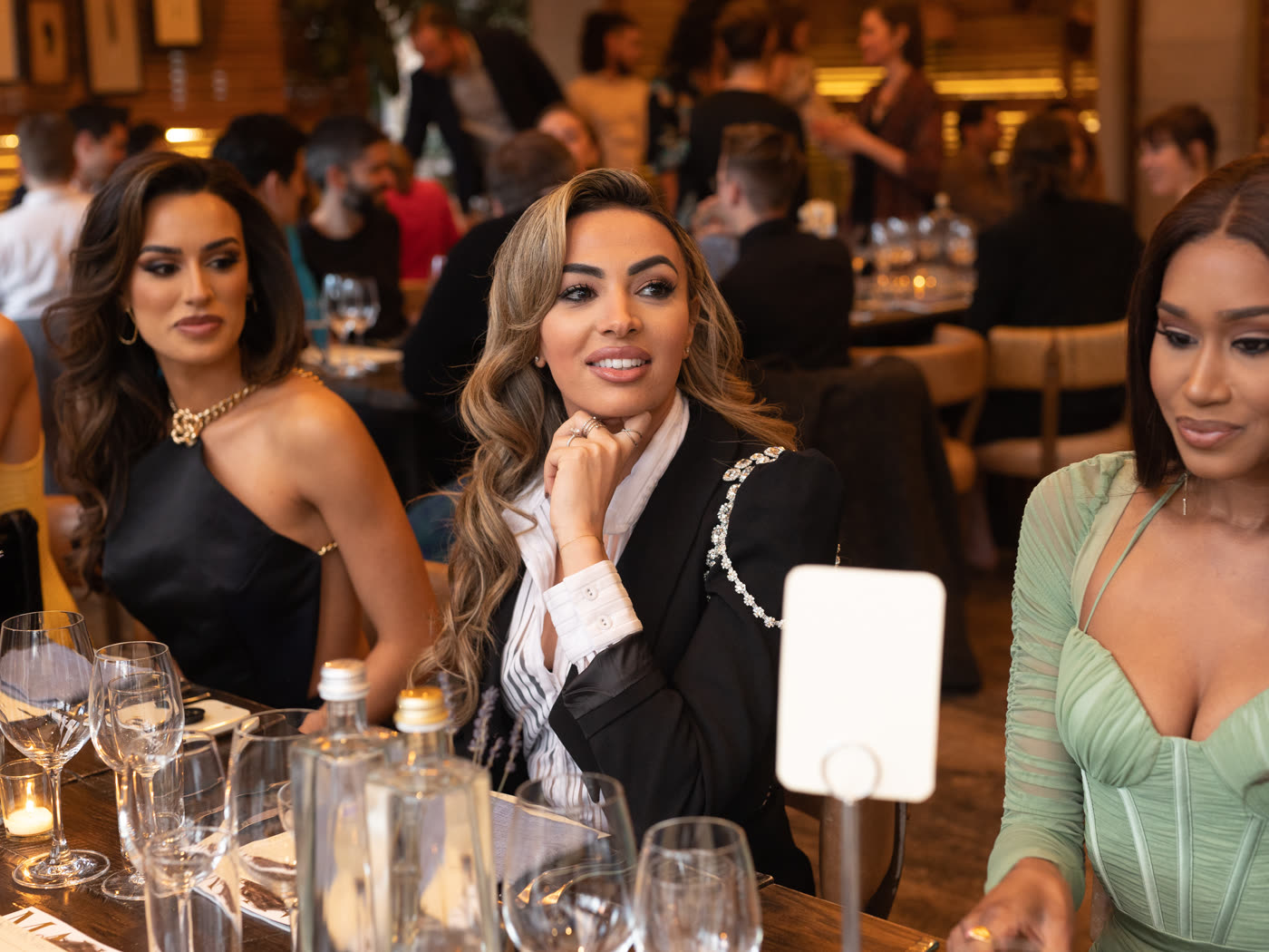 Three guests seated together at the dinner table during the Maxim cover party