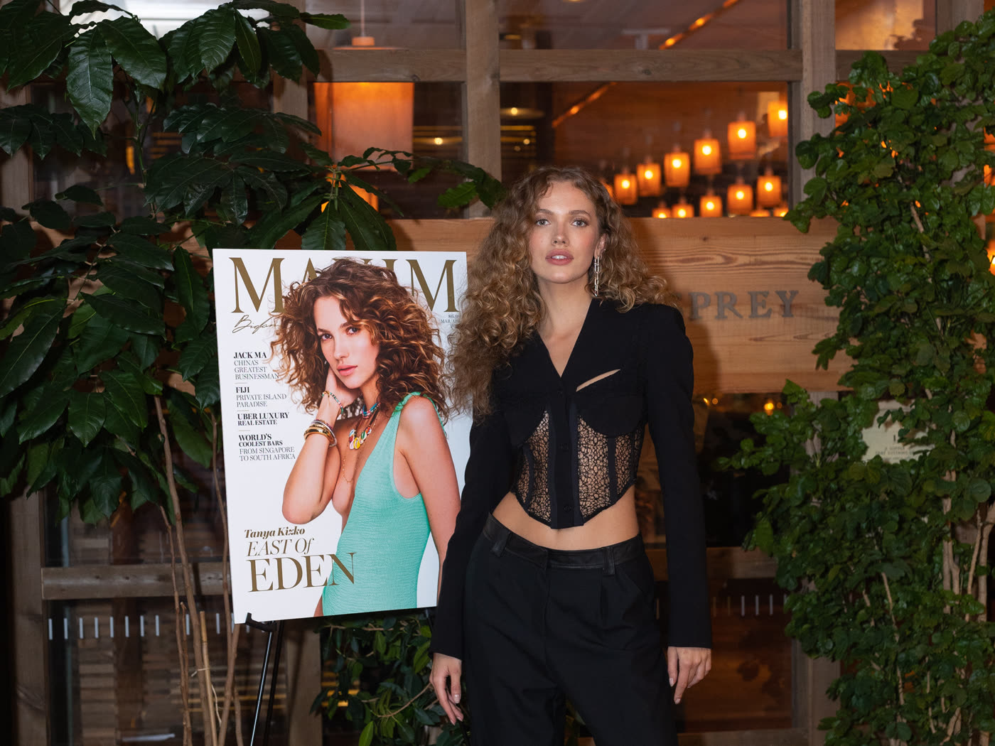The Maxim cover model standing beside her own cover on display at the party