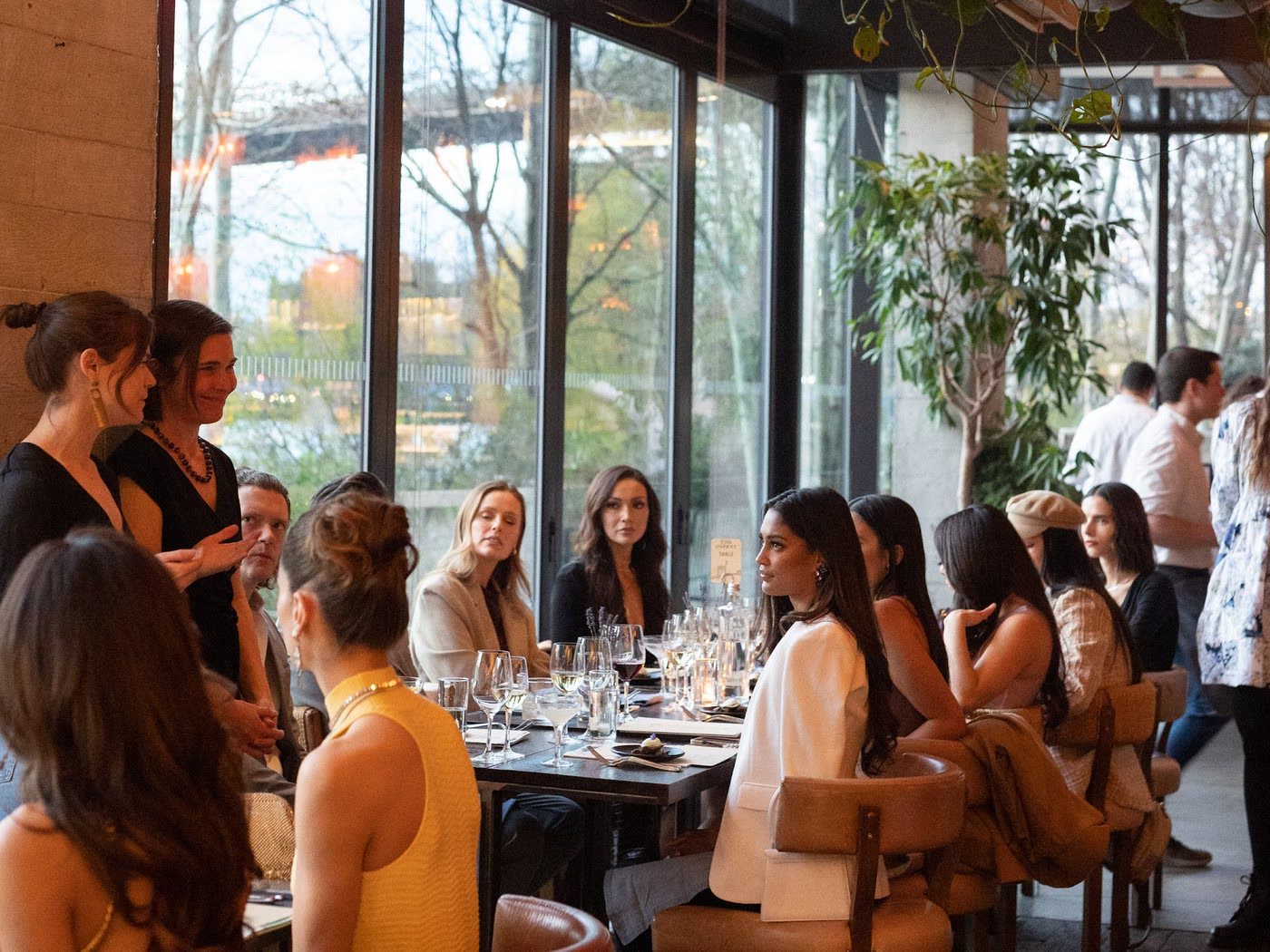 Guests seated along a long communal table at the Maxim cover party, The Osprey, 1 Hotel Brooklyn Bridge, New York
