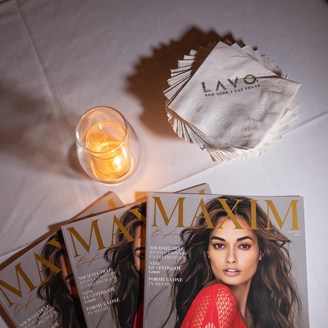 Copies of Maxim's September 2022 issue laid out with LAVO napkins at the cover party