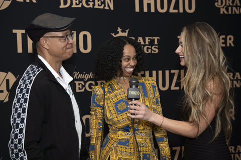 An on-carpet host interviewing arriving guests with a branded microphone