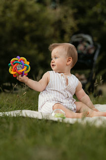 Baby spielt draussen mit bunter Rassel