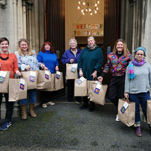 The Pass The Parcel team  smiling with gift bags in hands smiling at the front of the church