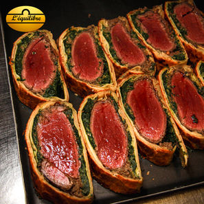 Filet de bœuf en croûte avec duxelles de champignons et épinards, servi avec sa garniture et son jus corsé.