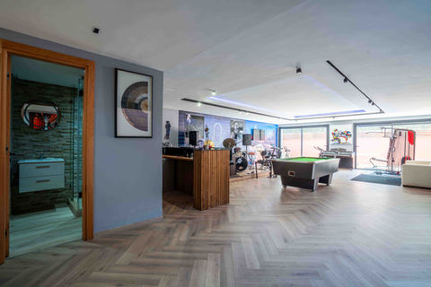 Grande salle de loisirs avec billard, coin musique, espace détente et large baie vitrée laissant entrer la lumière naturelle.