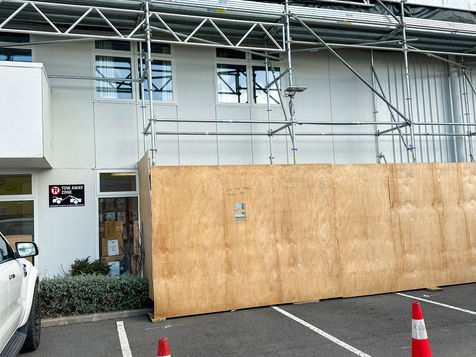 Building exterior with scaffolding, wooden barrier in parking lot BASELYFT SCAFFOLDING