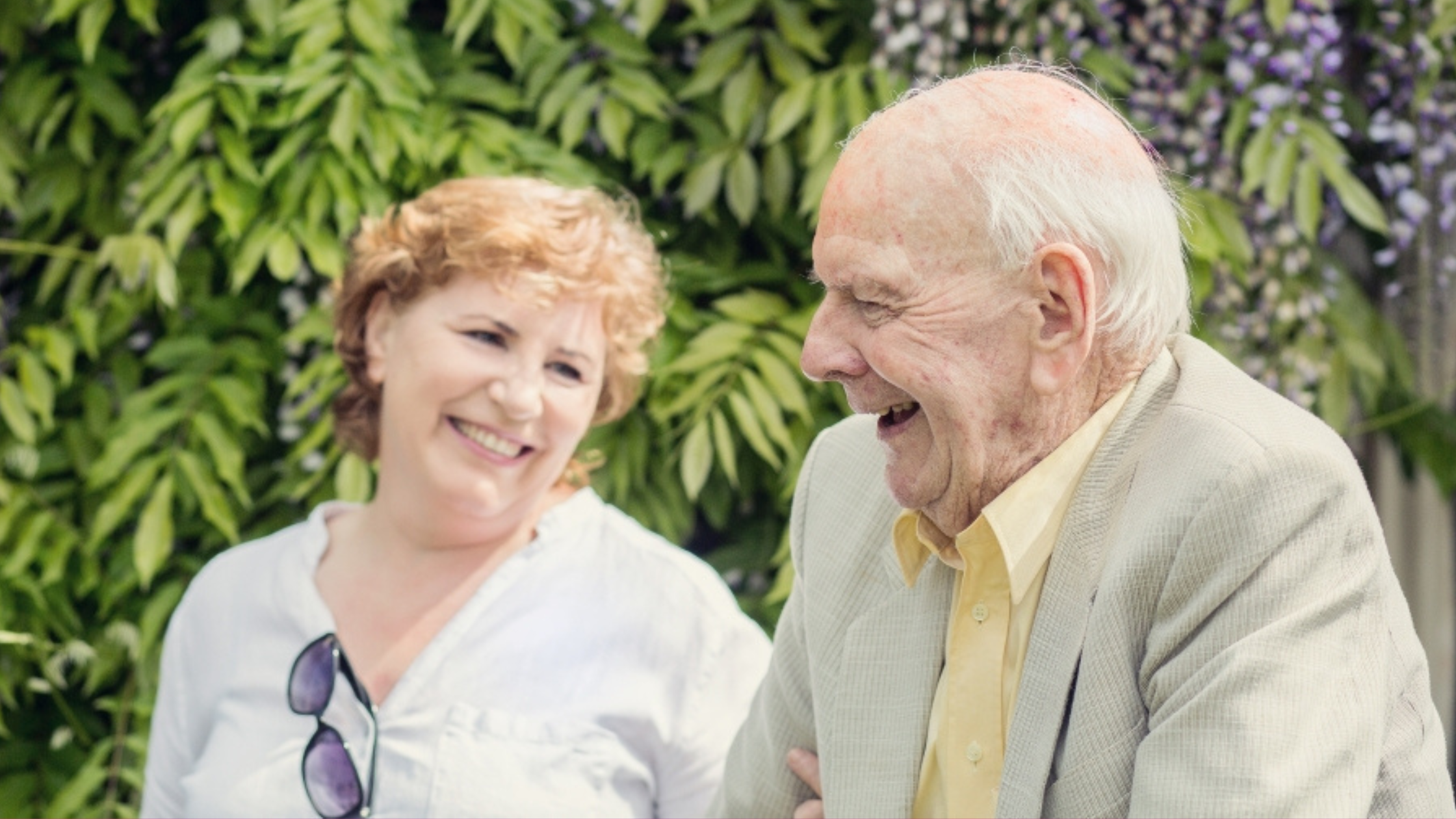 Elderly man sat with home carer in the garden drinking tea