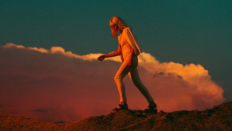woman walking over rocks with cloud in the background