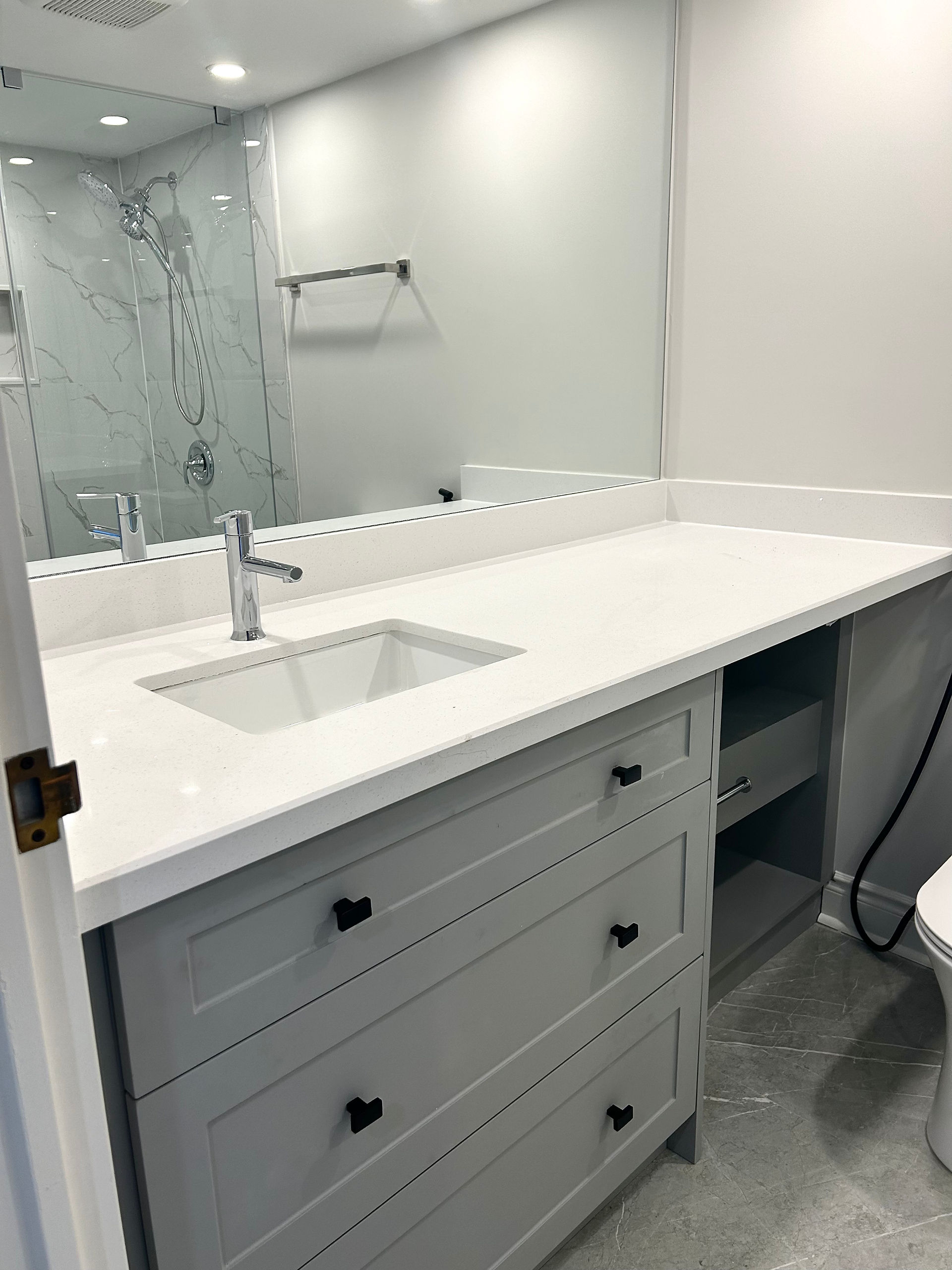 Full condo bathroom renovation completed by Reno Rabbit with standing shower and custom vanity.