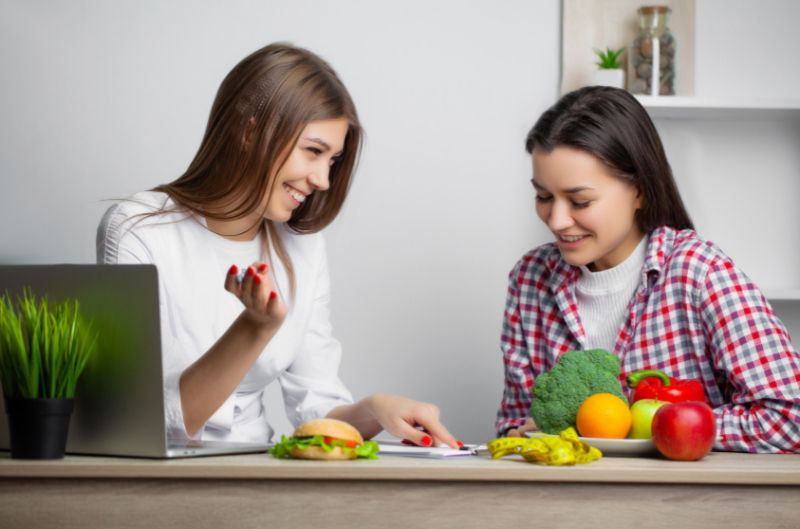 two women talking with food in front of them