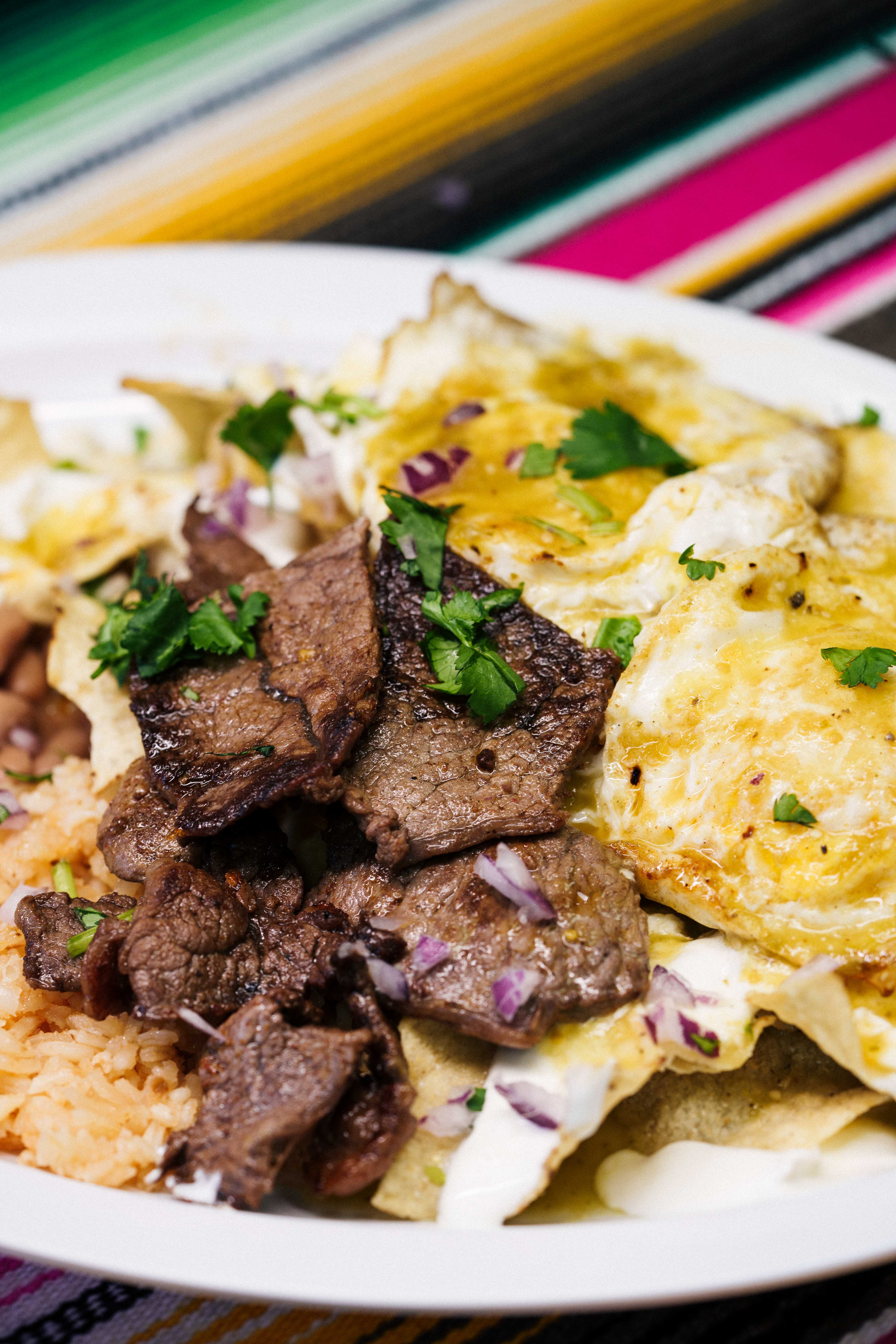 Chilaquiles con huevo y asada — chilaquiles topped with steak and fried egg