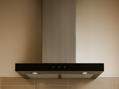 Coifa de parede moderna em inox e acabamento preto fosco, instalada sobre revestimento bege em cozinha planejada com iluminação embutida.