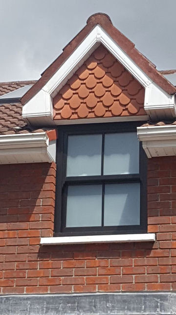 dormer window with black frames and red brick roofing