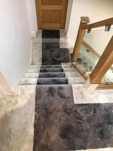 Dark grey carpet runner on light stone stairs