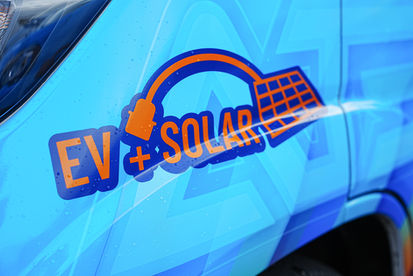 Close-up of EV and Solar graphics printed on blue company service vehicle
