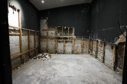 Commercial interior room under renovation with stripped walls and bare floorboards