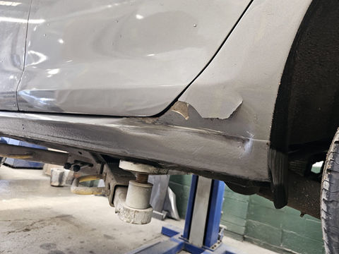 Damaged car side panel, showing repair process and supporting equipment. Shepperton Body Works Ltd