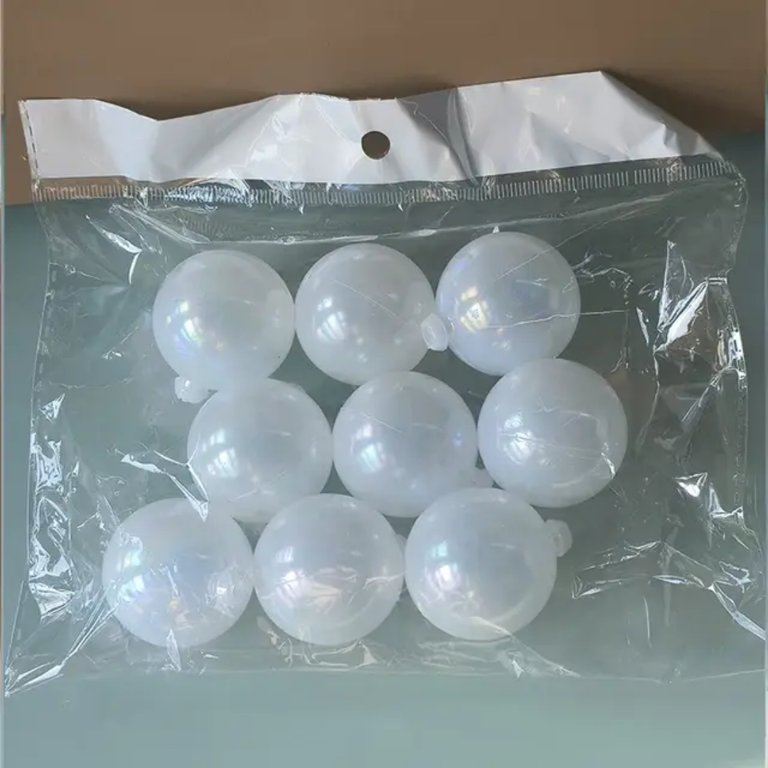 A transparent plastic bag holds a set of nine opaque white, hollow, sphere-shaped cake toppers.