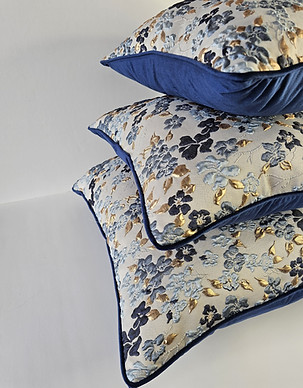 Stacked pillows with blue floral pattern, gold accents