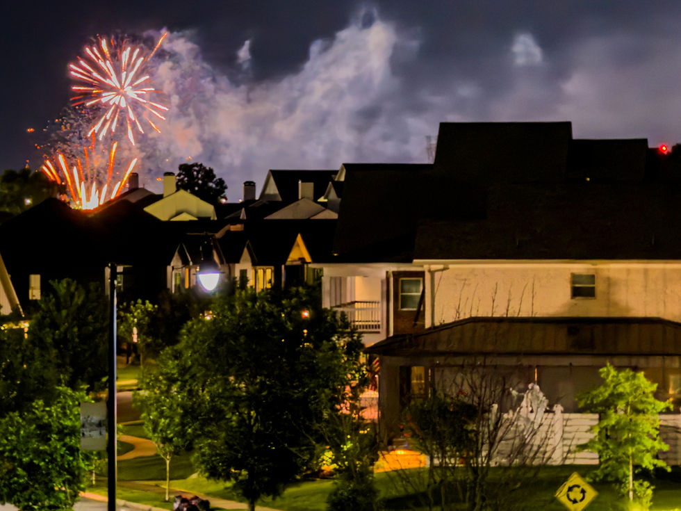 Neighborhood fireworks going off at night leaving smoke and sparks floating in the air.