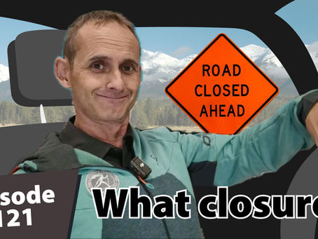 Matt Dayton smiling and turning the steering wheel inside a car with a “Road Closed Ahead” sign visible through the rear window and snowy mountains in the background. Text reads “Episode 121” and “What closure?”