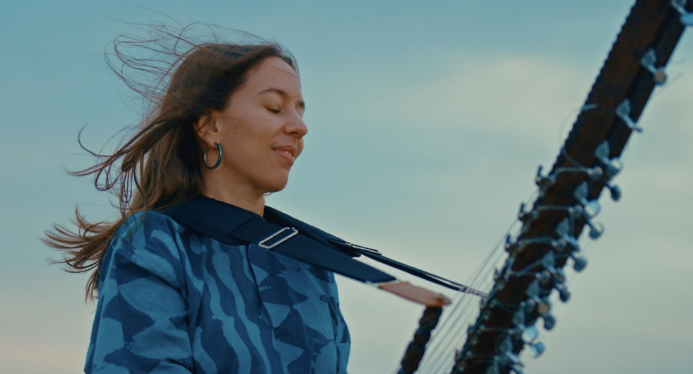 Rares sont les artistes qui mêlent tradition et innovation comme Sophie Lukacs, alliant la kora à un cœur d'auteure-compositriceinterprète et à une voix maîtrisant quatre langues. Née à Budapest et installée à Montréal, Sophie a commencé son parcours musical par le violon classique et les chants folkloriques hongrois, appris auprès de sa grand-mère Eva Fahidi, une survivante de l'Holocauste dont la résilience et le talent artistique ont profondément marqué sa compréhension du pouvoir guérisseur de la musique. Mais c'est une rencontre fortuite au Burkina Faso, durant ses études universitaires, qui a tout changé : sa première initiation à la kora, la harpe d'Afrique de l'Ouest. L'appel de cette harpe à 21 cordes était si fort qu'elle ne pouvait s'en détacher. Captivée, mais aussi profondément appréhensive, elle ressentait une grande crainte : la kora est un instrument traditionnellement transmis de génération en génération au sein des familles de djeli (griots), une tradition vénérée qu'elle n'osait aborder, en tant que femme et étrangère. Pendant des années, elle s'est consacrée à l'écoute, s'imprégnant du riche répertoire de la kora. Puis, comme un signe du destin, sur le quai du métro new-yorkais – à la station Columbus Circle – elle a entendu le son si particulier d'une kora résonner dans la station. En suivant la musique, elle a rencontré le maître Malang Jobarteh. C'était le signe qu'elle attendait.