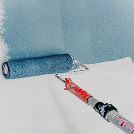 Blue paint being rolled onto an empty white wall