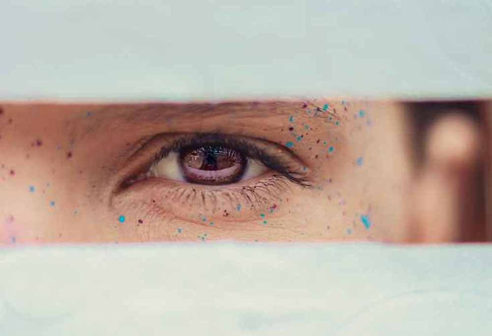 crop woman brown eye with drops of paint on face