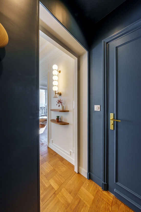 Entrée avec porte bleu profond, parquet en bois et vue sur la pièce de vie