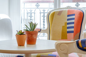 Fauteuil coloré avec coussin graphique, table ronde blanche et plantes dans le séjour