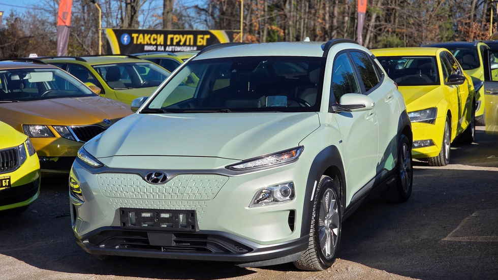 Hyundai Kona Electric SUV в светлозелено, наличен за продажба в автокъща Такси Груп БГ в България, напълно проверен употребяван електромобил, паркиран сред автомобили Škoda, модерен компактен електрически SUV готов за регистрация
