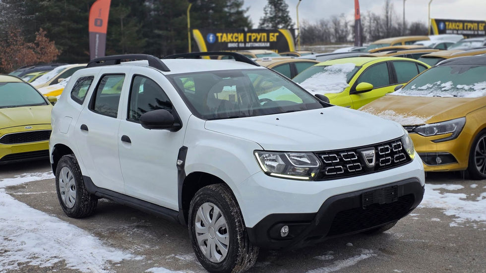 Dacia Duster такси – Taxi Group BG, България — преден тричетвърти изглед на бял SUV Dacia Duster, паркиран в заснежен автопарк на Taxi Group BG, с много таксиметрови автомобили на заден план