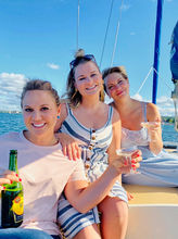 Three young ladies having a toast aboard sailboat Michele