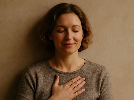 Das Bild zeigt eine Frau, die eine Hand auf ihre Brust legt und mit geschlossenen Augen und einem entspannten Lächeln in sich hinein spürt.