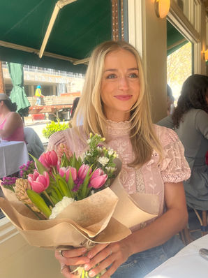 Sally Rychlak pink shirt holding assorted flowers 