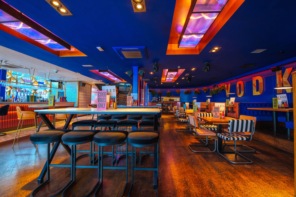 Captivating bold, colourful, contemporary bar in Clapham, London with deep blue and gold elements and retro style furniture