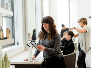 Dona de salão usando um tablet para conferir as contas do MEI