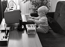 Commodore 16 – můj syn u mého prvního počítače na černobílé fotografii z roku 1988 / My son beside my first Commodore 16, black-and-white photo from 1988