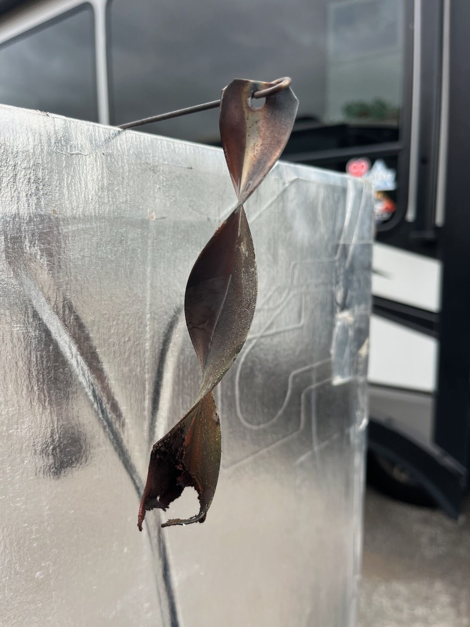 This metal strip was located at the bottom of the refrigerator exhaust chimney near the heating elements. It got hot enough to melt the metal strip and posed a fire hazard if the safety switch breaker hadn't tripped the unit off when we turned it on.