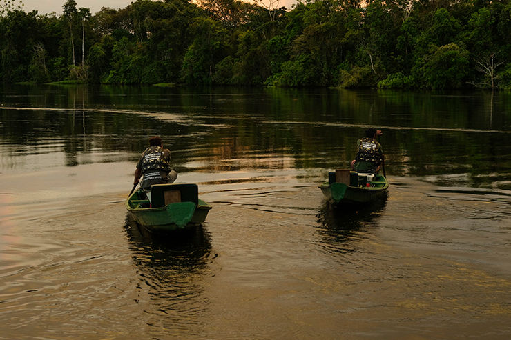 Imagem de homens navegando em rio.