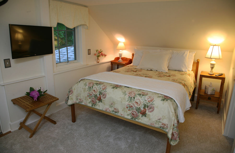 The charming Chickadee Suite with pretty floral bedspread on the queen bed at the Morning Glory Inn bed and breakfast in York, Maine.