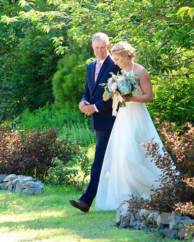 Father walking daughter through a wooded enclave to her wedding