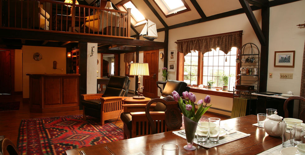 The interior of the great room at the Morning Glory Inn located on the coast of Southern Maine in York Harbor features a woodstove and an exposed wooden bean ceiling.