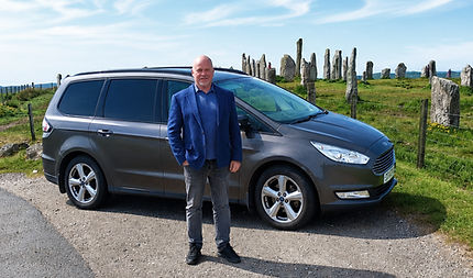 DRiver with car before tour of the isle of Lewis, Cruise ship in the background in Stornoway. 