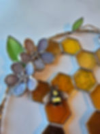 Close up view of a 10-inch circular honeycomb stained glass piece with purple flowers and bees.
