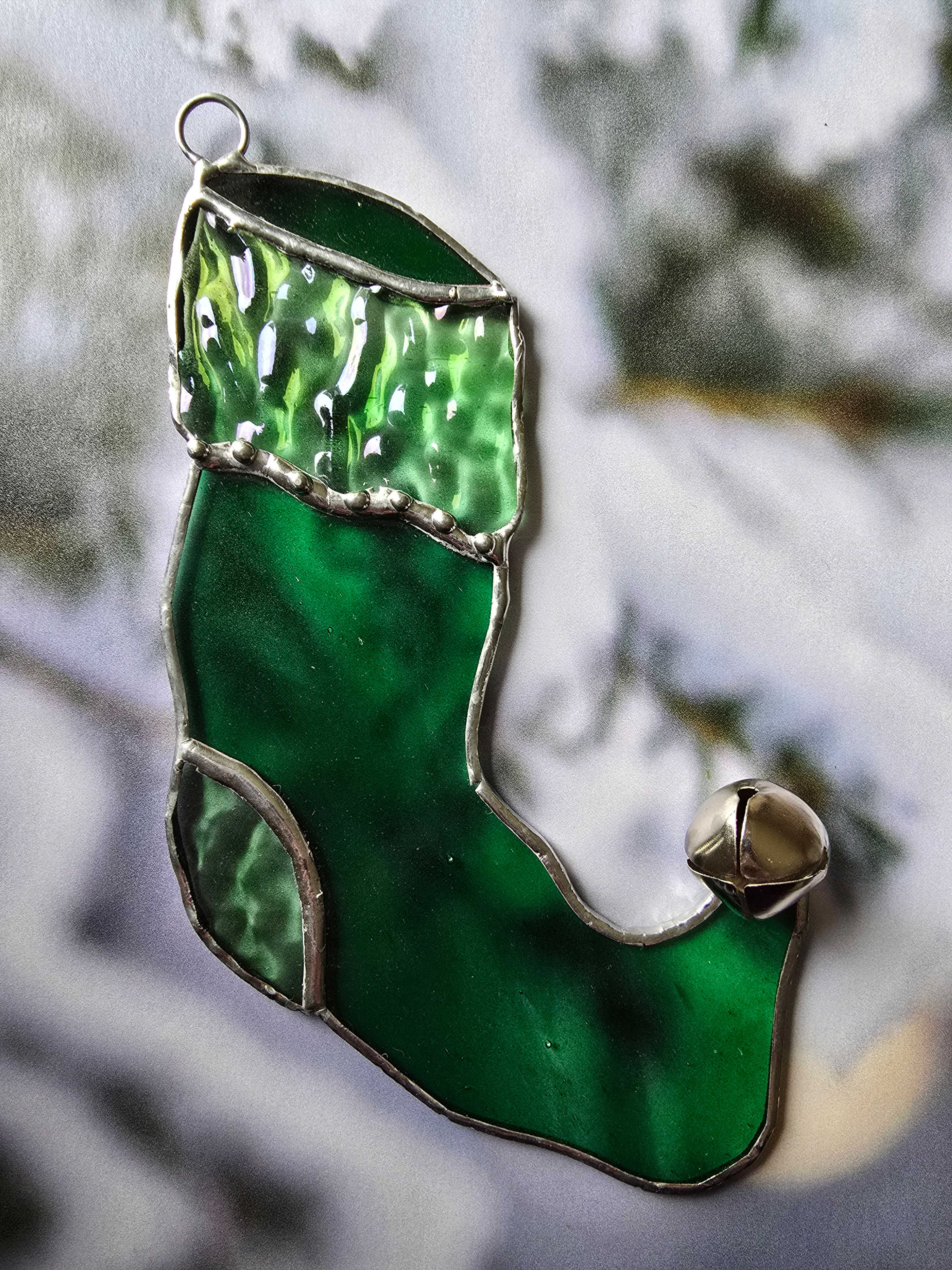 Green Stained Glass Christmas Stocking Ornament Hanging on a Snowy Pine Tree Background