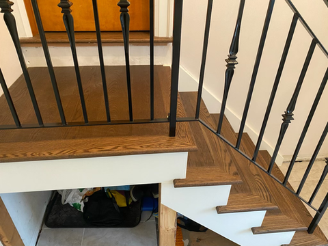 Light brown red oak staircase recapped. split level stairs with landing, left side open with black wrought iron spindles.