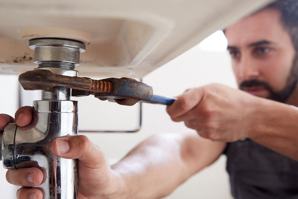 Male plumber fixing pipes under sink
